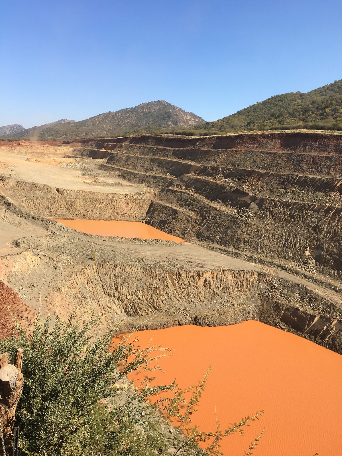 Terraced open-pit mining operation with mountain backdrop